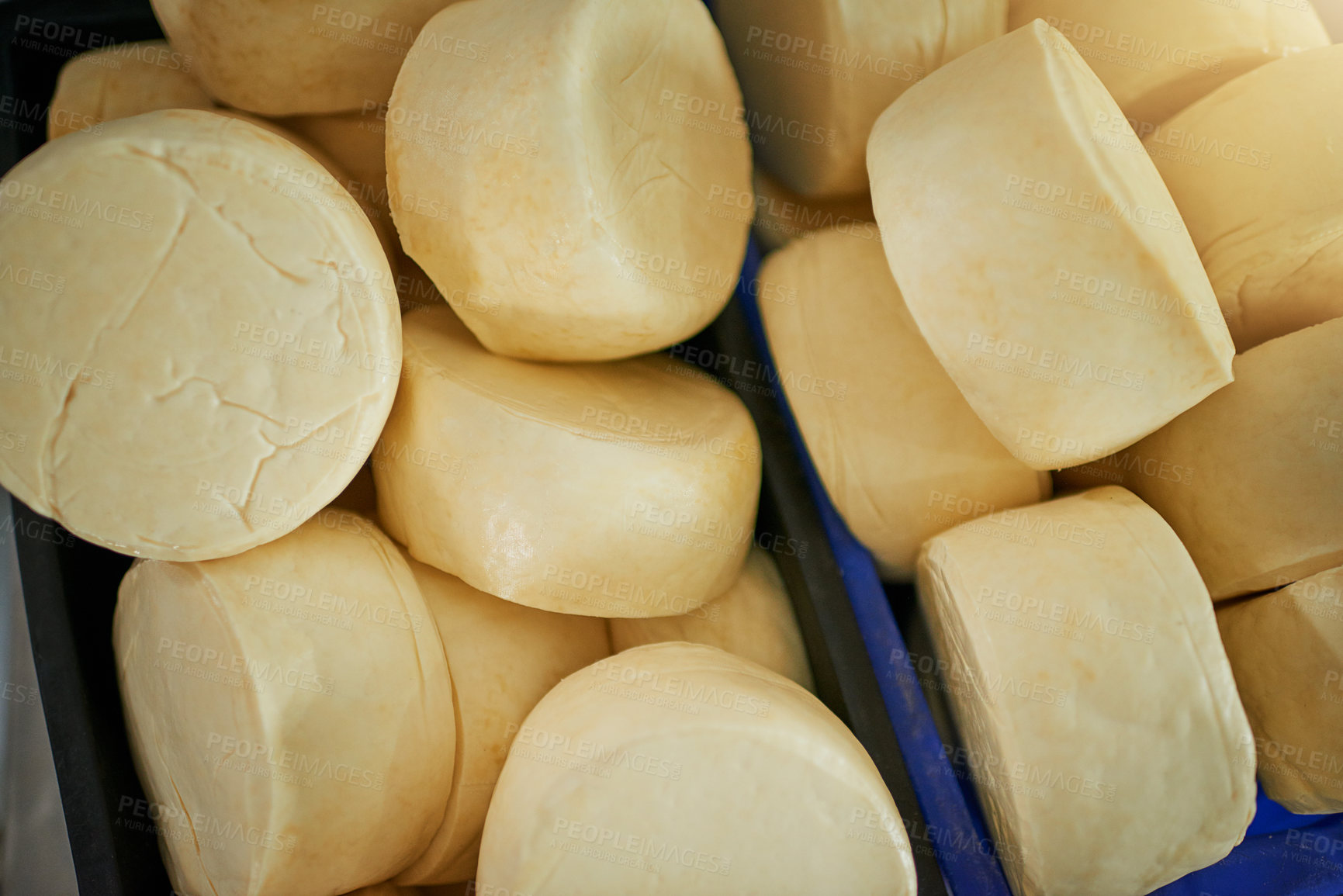 Buy stock photo Heap of round raw cheese wheels in a crate ready for packing and delivery. Export of dairy products from natural raw materials. Cheese wheels in a box in a factory on a dairy farm from above