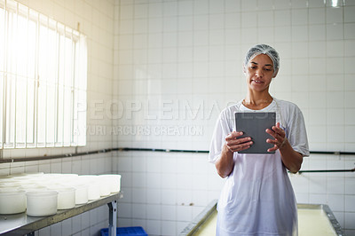 Buy stock photo Cropped shot of a young female farm worker using a tablet while working in a factory on the farm