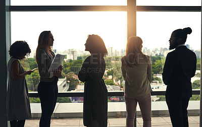 Buy stock photo Cropped shot of a group of businesspeople standing in front of a large window in their office