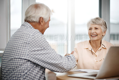 Buy stock photo Cropped shot of an affectionate senior couple shaking hands while working on their finances at home