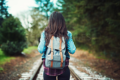 Buy stock photo Rearview shot of an unrecognizable woman walking on train tracks outdoors