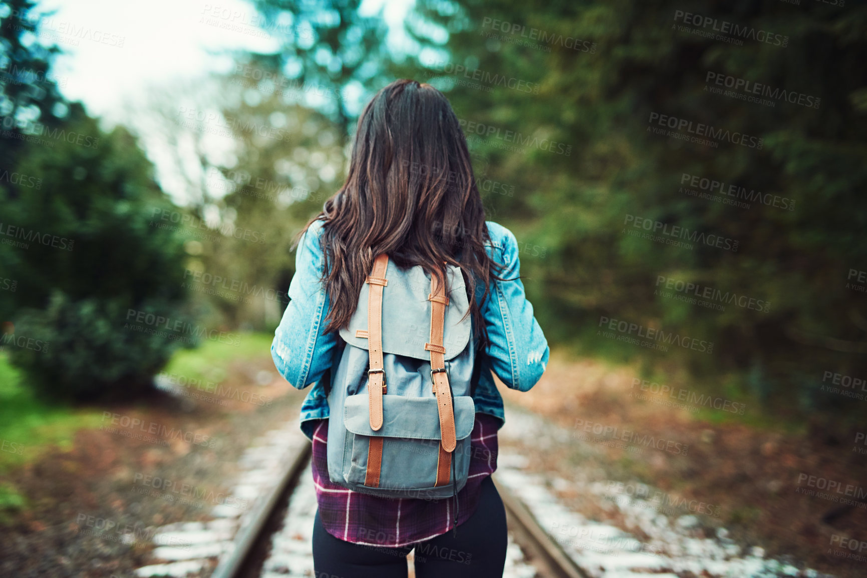 Buy stock photo Rearview shot of an unrecognizable woman walking on train tracks outdoors