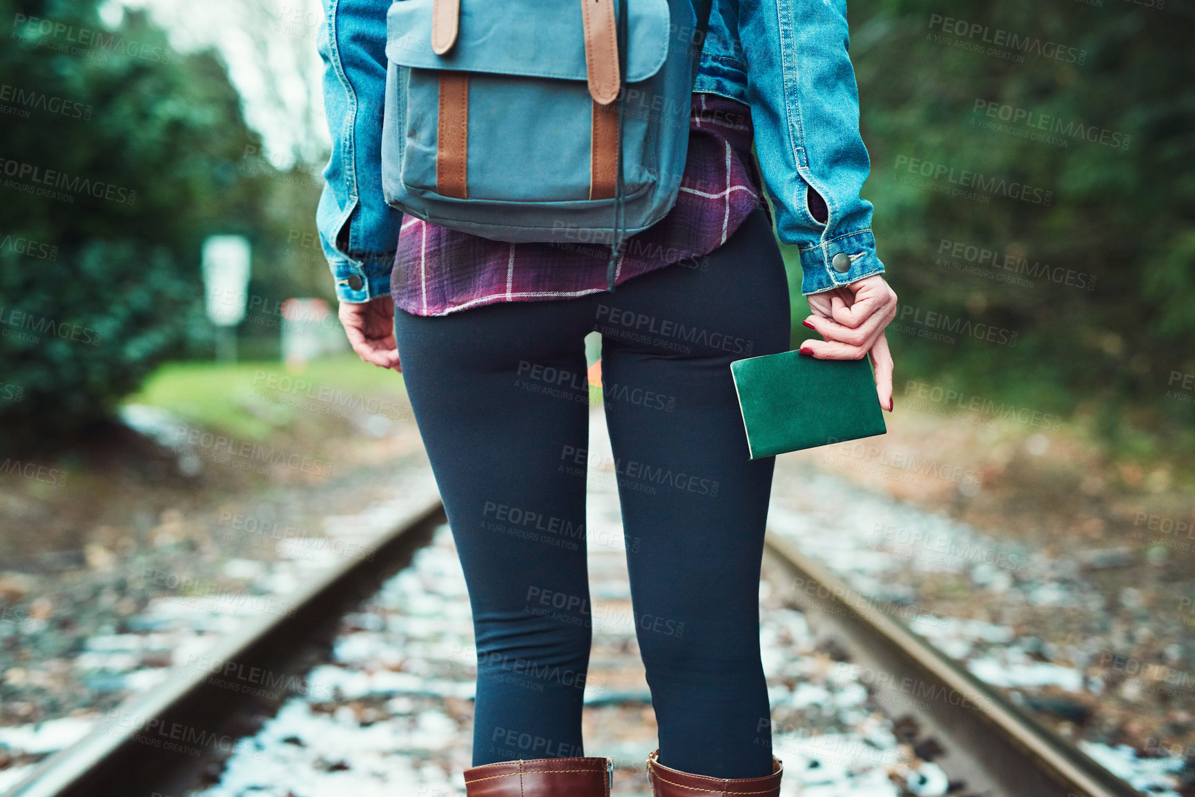 Buy stock photo Rearview shot of an unrecognizable woman walking on train tracks outdoors