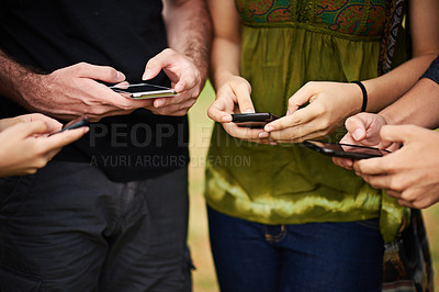 Buy stock photo Cropped shot of a group of college students using cellphones outside