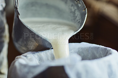 Buy stock photo Cropped shot of an unrecognizable male farmer pouring unprocessed milk into a container inside a barn