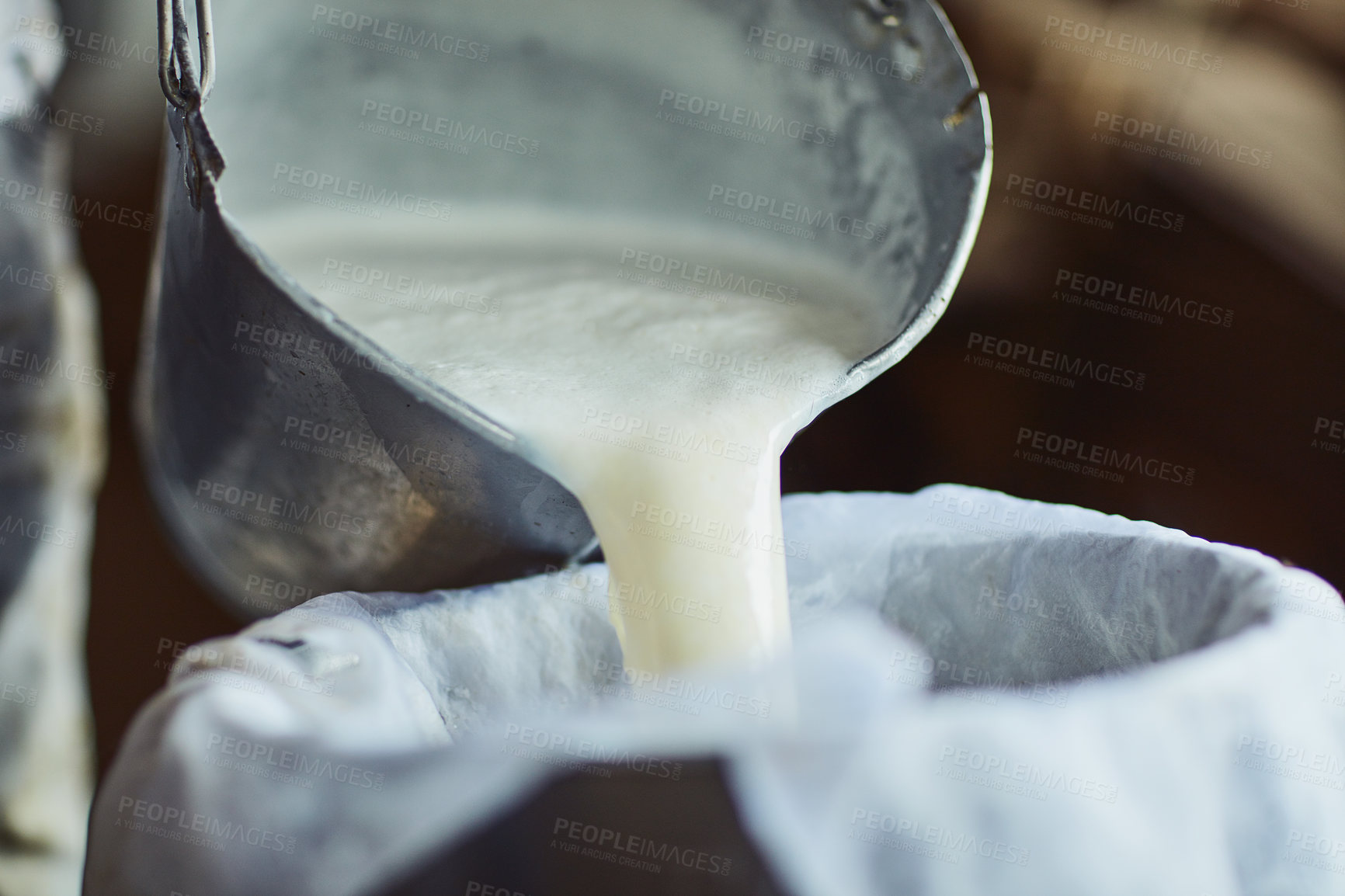 Buy stock photo Cropped shot of an unrecognizable male farmer pouring unprocessed milk into a container inside a barn