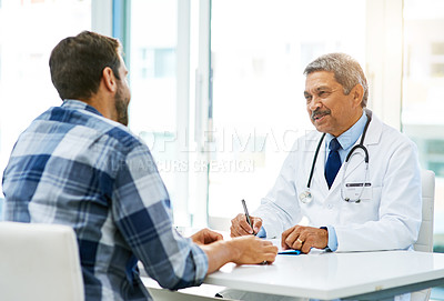 Buy stock photo Shot of a confident mature male doctor consulting with a patient inside of his office during the day