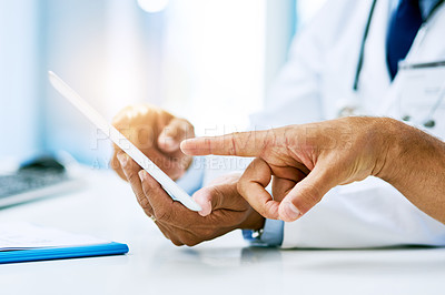 Buy stock photo Shot of an unrecognizable doctor and patient looking at test results on a digital tablet inside of a hospital during the day