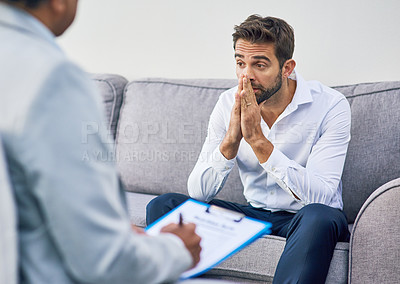 Buy stock photo Shot of an stressed out young man having a discussion with his doctor while being seated on a sofa inside of a doctor's office during the day