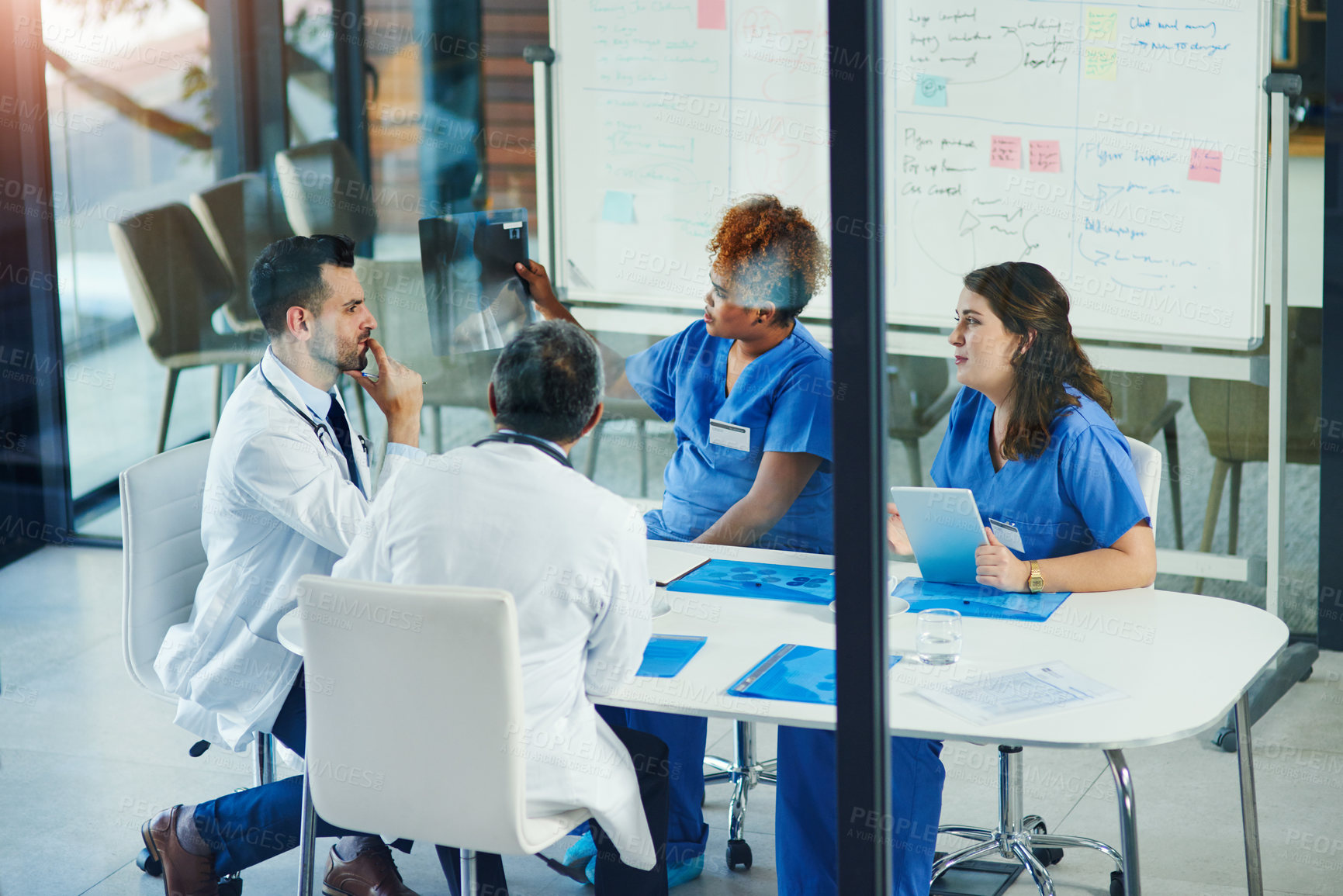 Buy stock photo Shot of a group of medical practitioners analyzing x-rays in a hospital