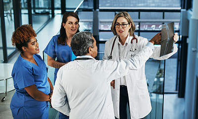 Buy stock photo Shot of a team of doctors discussing the results of an X-ray in a hospital