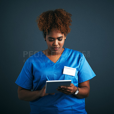 Buy stock photo Studio shot of a young doctor using a digital tablet against a gray background