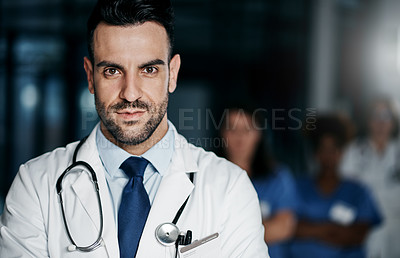 Buy stock photo Portrait of a confident young doctor working in a hospital with his colleagues in the background