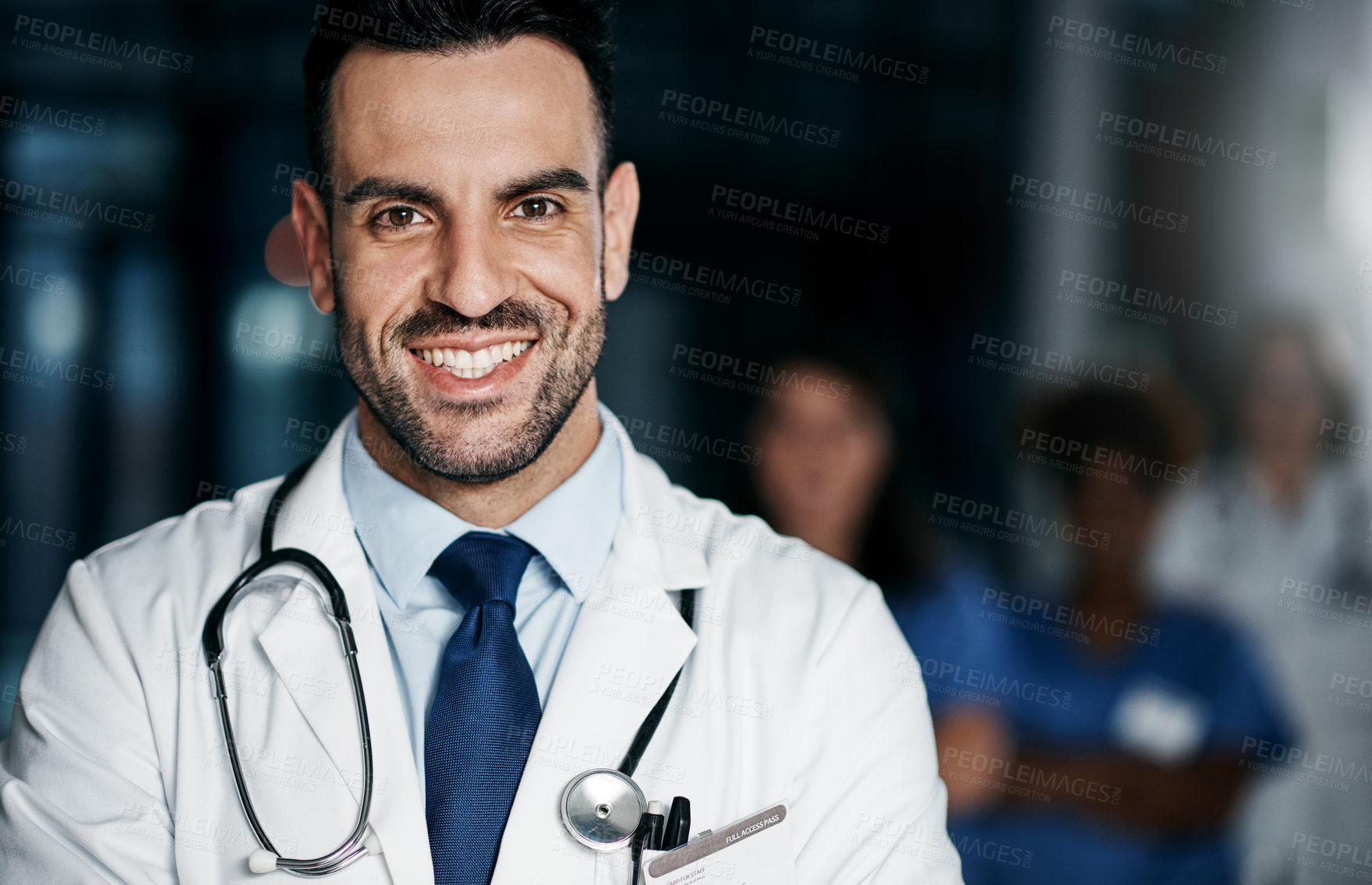 Buy stock photo Portrait of a confident young doctor working in a hospital with his colleagues in the background