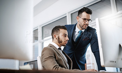 Buy stock photo Shot of two businessmen working together on a computer in an office