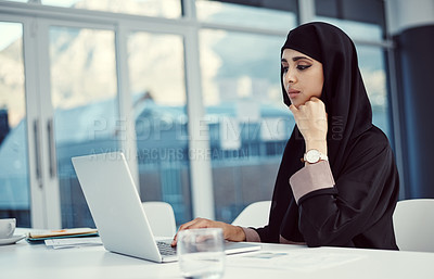 Buy stock photo Cropped shot of an attractive young arabic businesswoman working on her laptop in the office