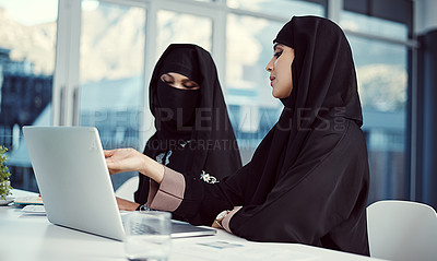 Buy stock photo Cropped shot of two young arabic businesswomen working on a laptop in their office