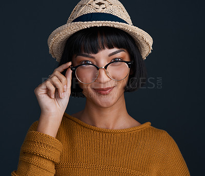 Buy stock photo Studio shot of an attractive young woman wearing glasses and a hat against a dark background