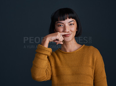 Buy stock photo Studio shot of an attractive young woman making a mustache with her finger against a dark background