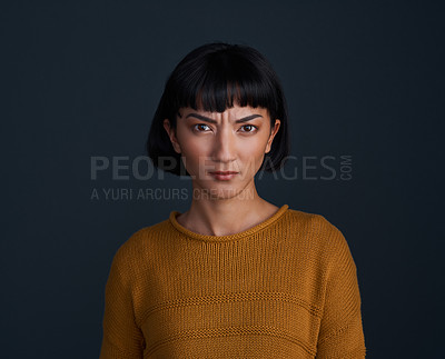 Buy stock photo Studio shot of an attractive young woman looking angry against a dark background