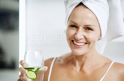 Buy stock photo Cropped shot of a mature woman holding a glass of water with cucumber in