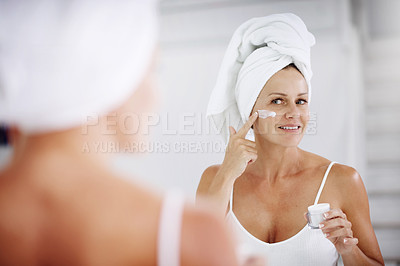 Buy stock photo Cropped shot of a mature woman applying moisturizer to her face
