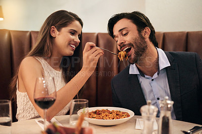Buy stock photo Romantic, date and woman feeding man spaghetti for dinner, supper and fine dining at a restaurant together. Couple, cute and happy lovers enjoying food, pasta and wine for valentines day