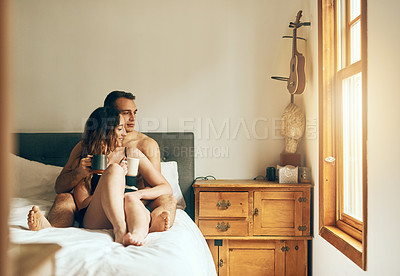 Buy stock photo Shot of an affectionate young couple having their morning coffee together in the bedroom at home