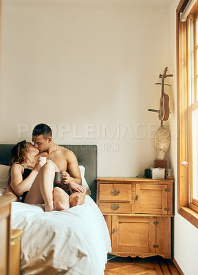 Buy stock photo Shot of an affectionate young couple having their morning coffee together in the bedroom at home