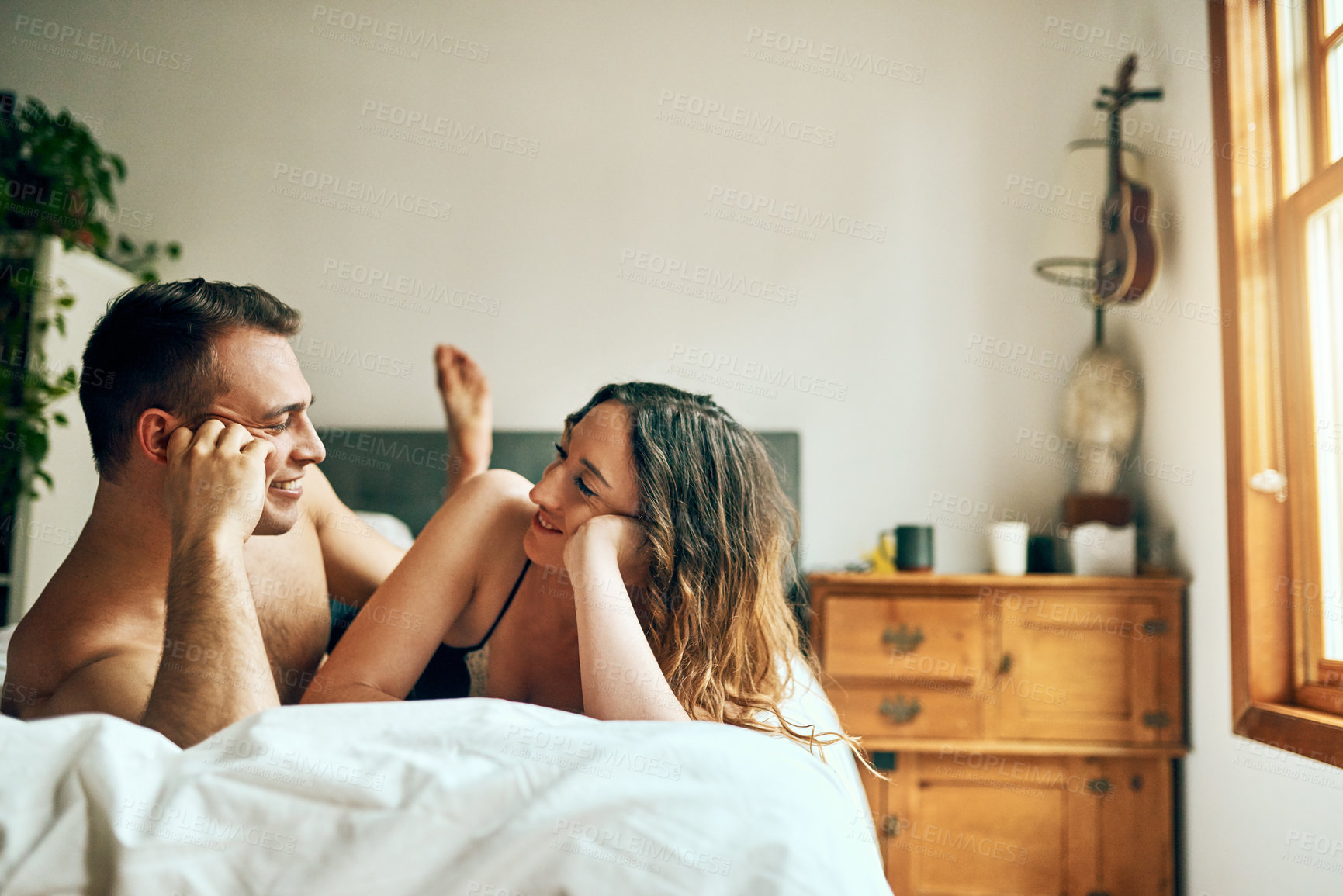 Buy stock photo Shot of an affectionate young couple spending a romantic morning in bed at home