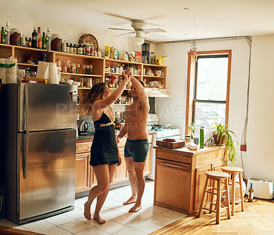 Buy stock photo Shot of a happy young couple dancing in the kitchen at home