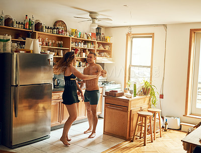 Buy stock photo Shot of a happy young couple dancing in the kitchen at home