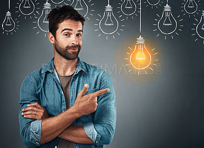 Buy stock photo Studio portrait of a handsome young man pointing towards an illustration of a lit light bulb against a grey background
