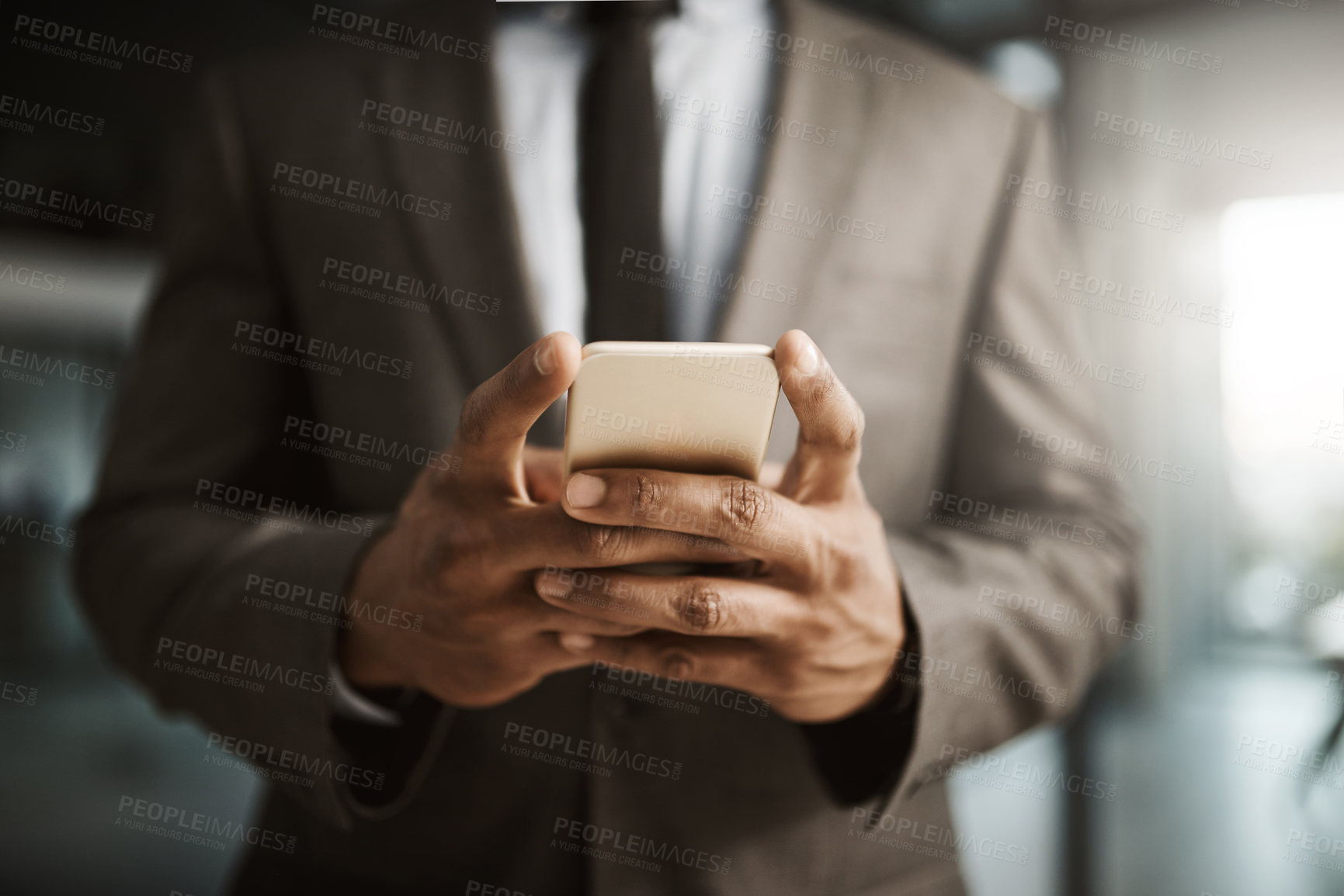 Buy stock photo Businessman texting on a phone to send a formal business sms text inside an office at work. African corporate executive professional male wearing a suit typing an email to his client online close up