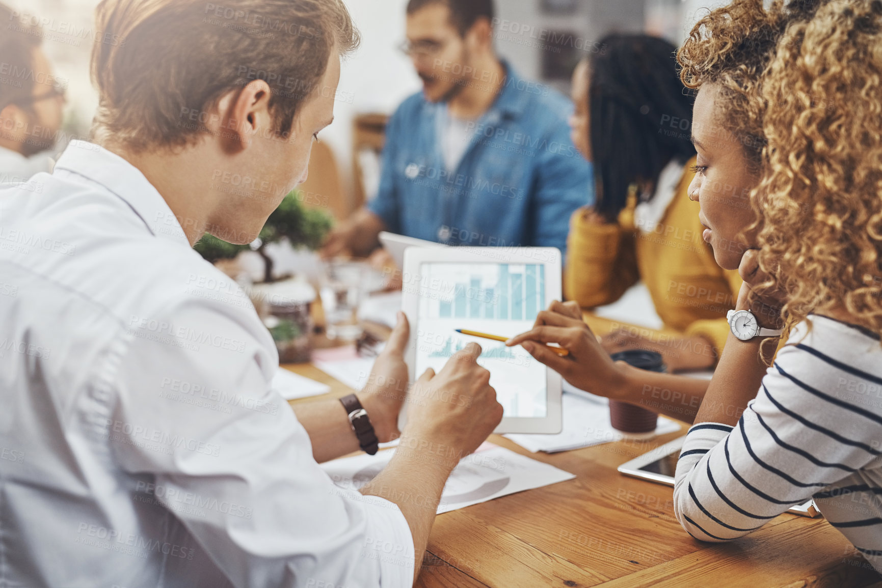 Buy stock photo High angle shot of colleagues discussing something on a digital tablet