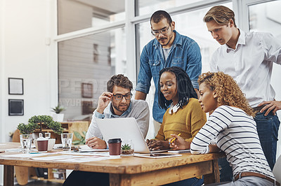 Buy stock photo Cropped shot of a group of businesspeople looking at something on a laptop