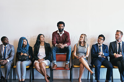Buy stock photo Shot of a group of confident businesspeople waiting in line for their interviews while a man sits on top of a chair inside of a office during the day