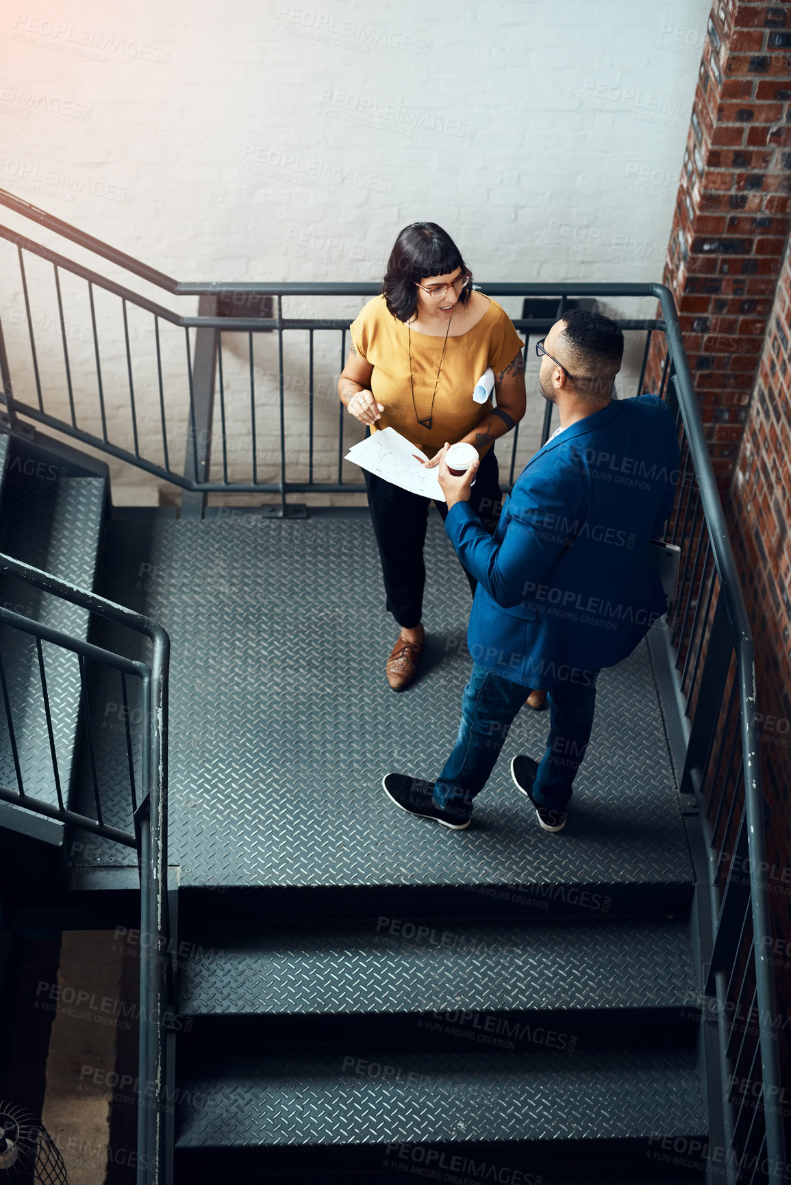 Buy stock photo Shot of two designers having a discussion on a staircase in an office