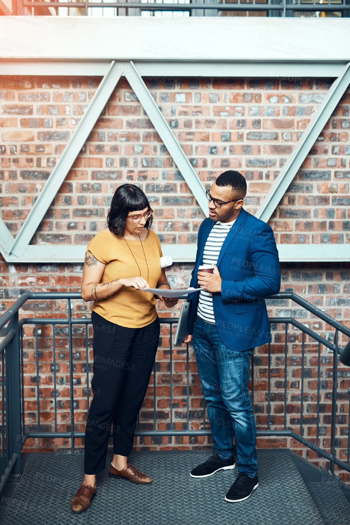 Buy stock photo Shot of two designers having a discussion on a staircase in an office