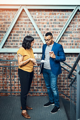 Buy stock photo Shot of two designers having a discussion on a staircase in an office