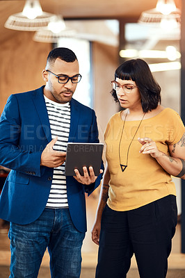 Buy stock photo Shot of two designers working on a digital tablet together in an office