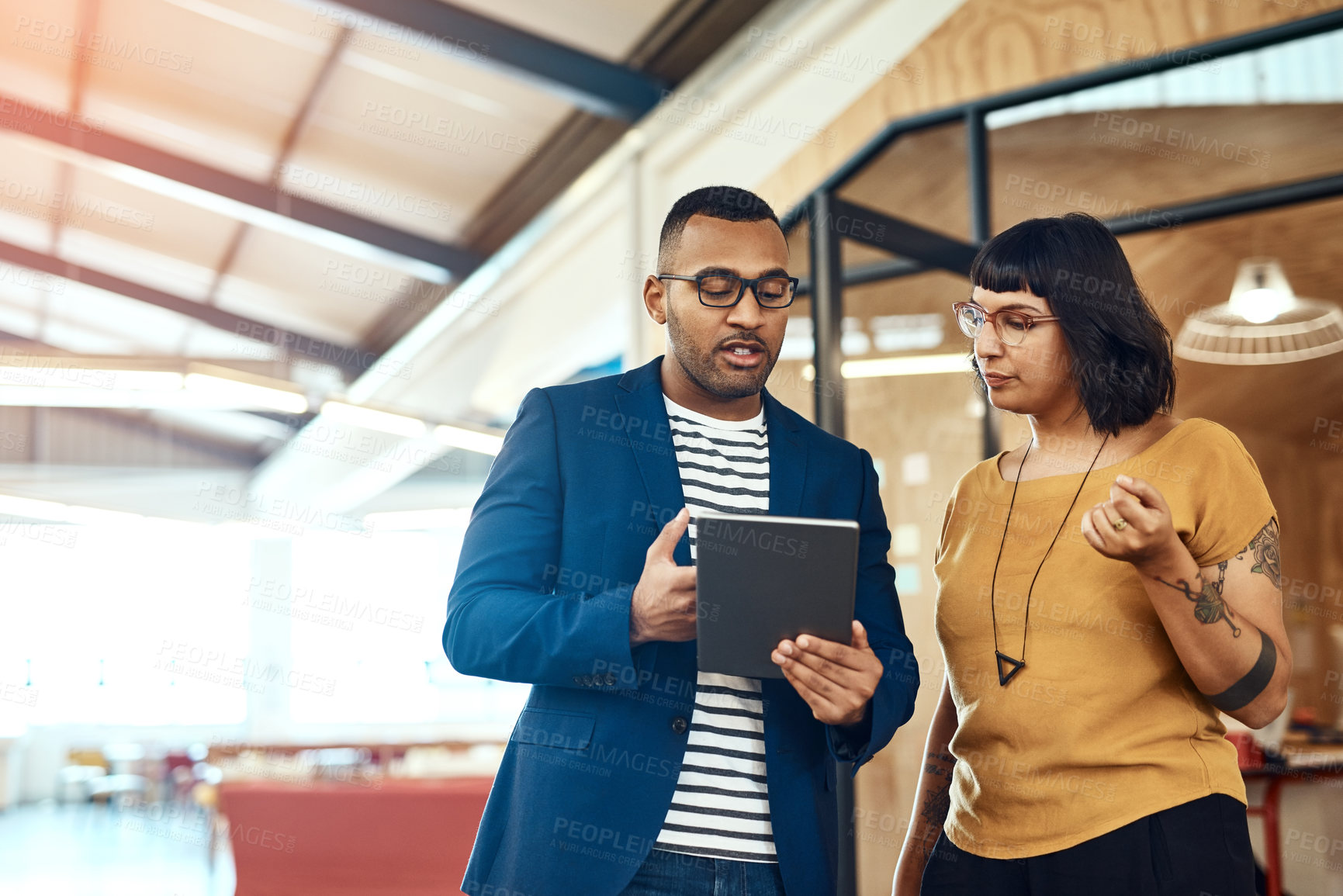 Buy stock photo Shot of two designers working on a digital tablet together in an office