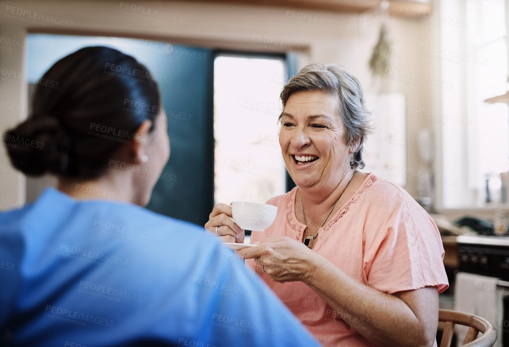 Buy stock photo Retirement, caregiver and happy woman in kitchen for support, kindness and healthcare. Tea, talking and medical worker or nurse with senior female person in home for conversation, advice or chat