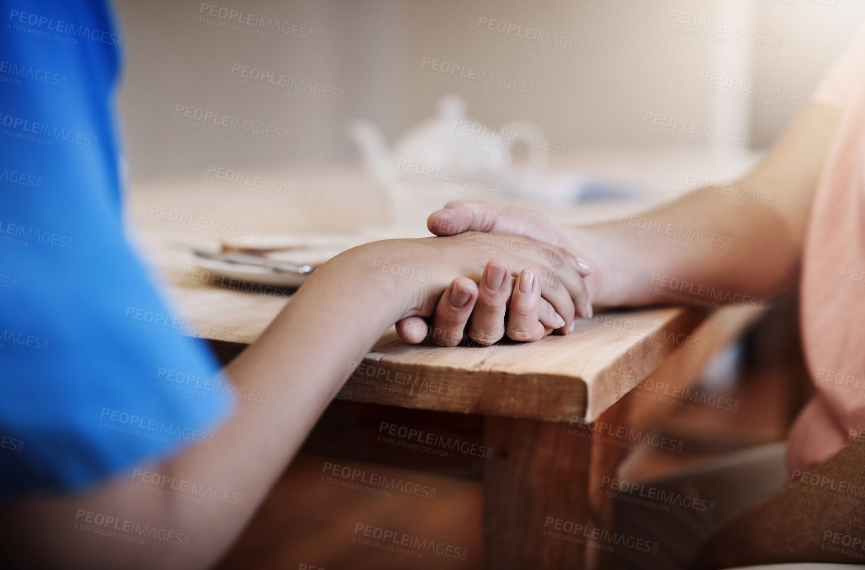 Buy stock photo People, holding hands or help in nursing home for support, empathy or hope in living room. Caregiver, woman or elderly care at wooden table for grief counselling, trust or mental health in retirement