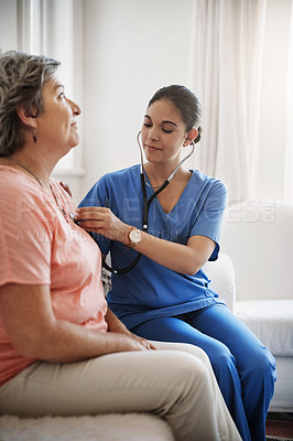 Buy stock photo Cropped shot of an attractive young female nurse examining a senior patient with a stethoscope