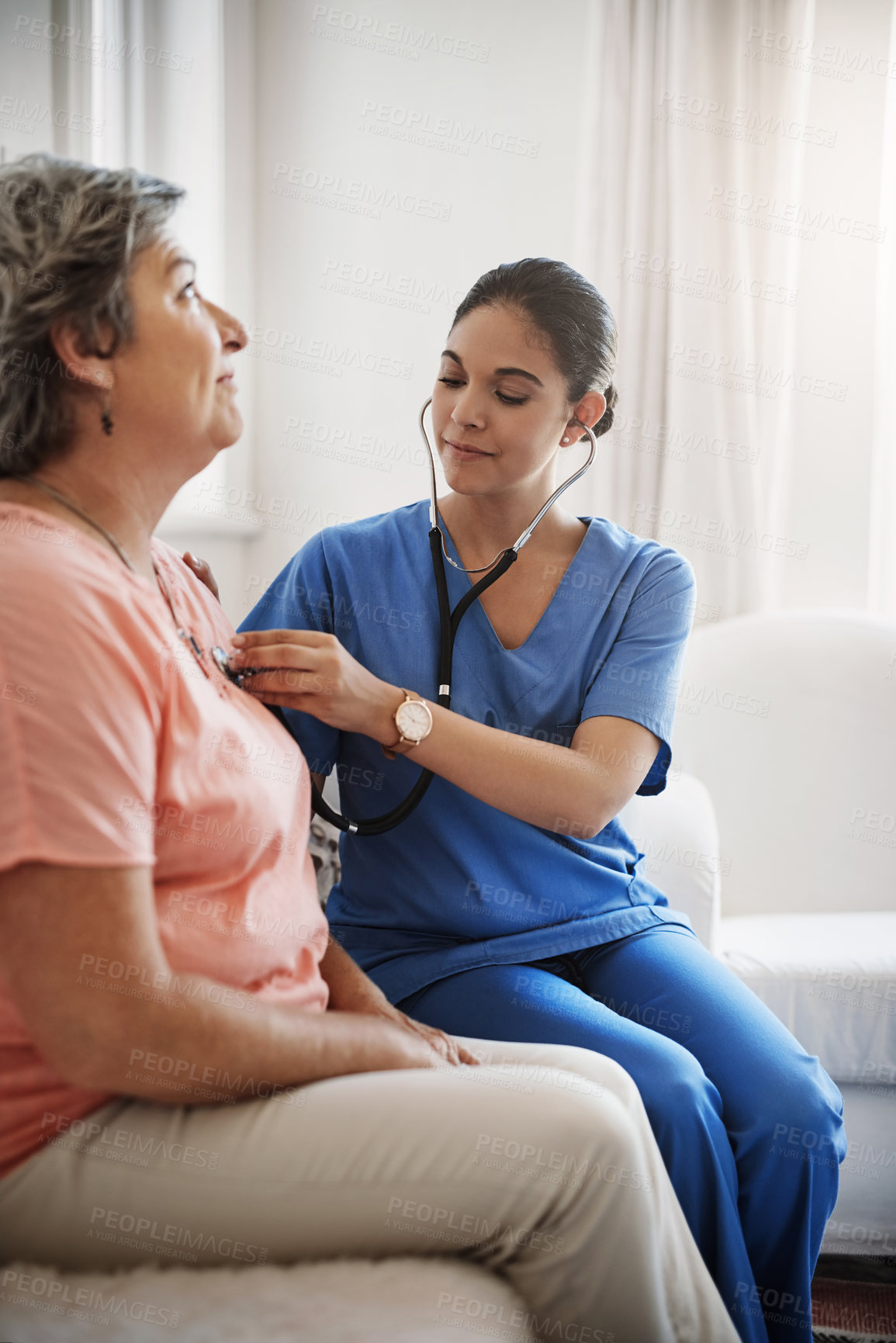 Buy stock photo Cropped shot of an attractive young female nurse examining a senior patient with a stethoscope