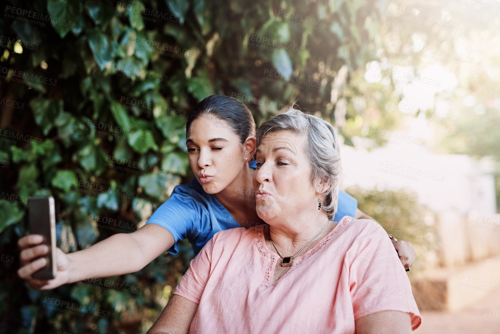 Buy stock photo Cropped shot of an attractive young female caregiver taking a selfie with a senior patient outside