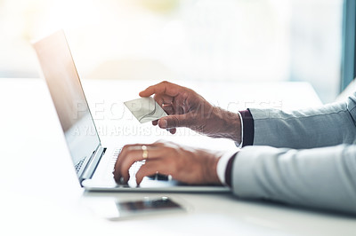 Buy stock photo Cropped shot of an unrecognizable businessman holding his credit card while using a laptop at his desk