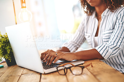 Buy stock photo Cropped shot of an unrecognizable young woman using her laptop on a wooden table