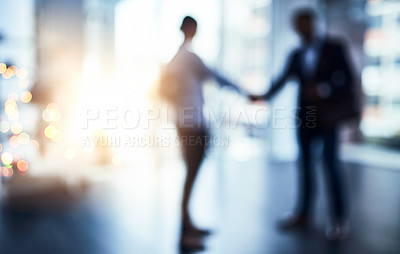 Buy stock photo Defocused shot of two businesspeople shaking hands in an office